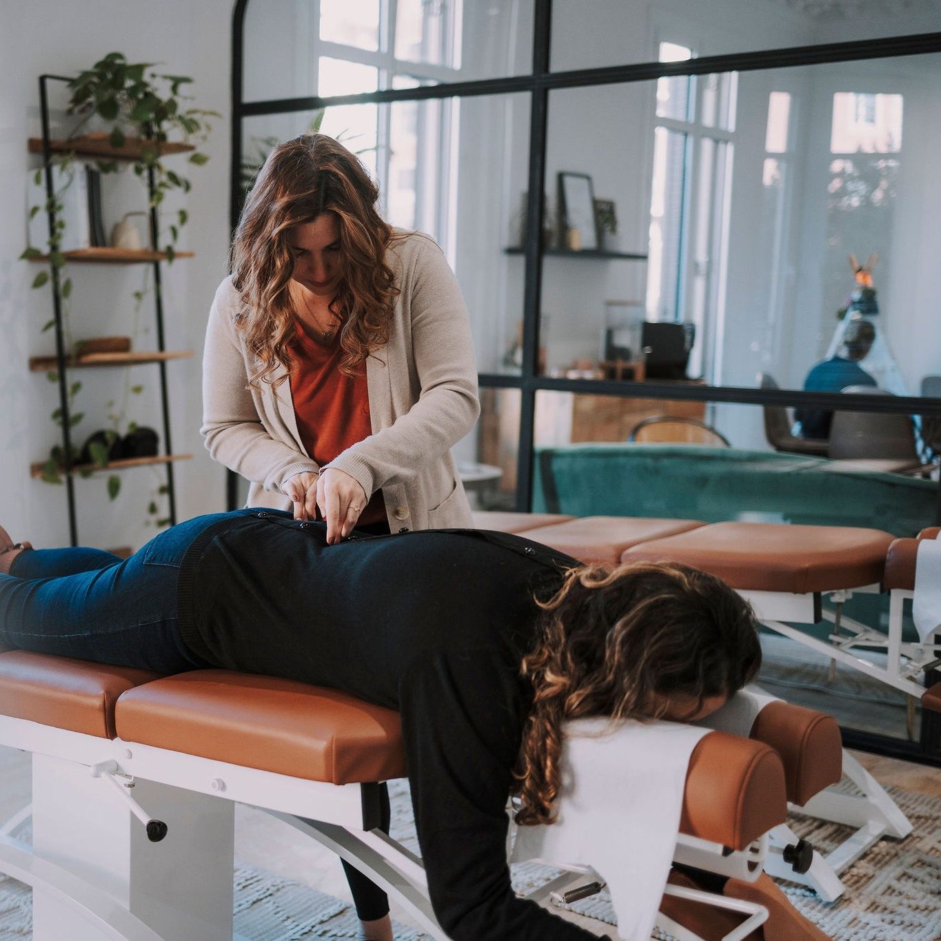La Dra. Kelli Turelli ajustando a una mujer en la camilla en illumINNATE Chiropractic Studio, Barcelona