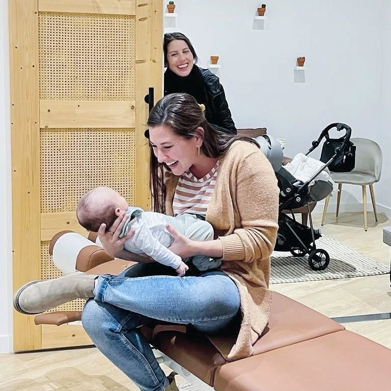 La Dra. Kelli Turelli sosteniendo a un recién nacido durante una primera revisión suave en illumINNATE Chiropractic Studio, Barcelona